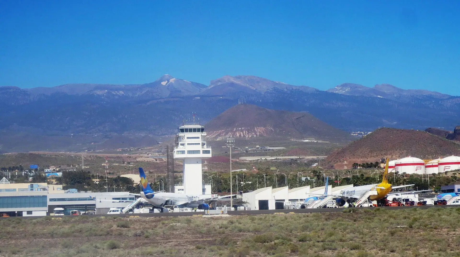 Torre de control y terminal del aeropuerto de Tenerife Sur con aviones en la plataforma y las cumbres del sur de la isla al fondo