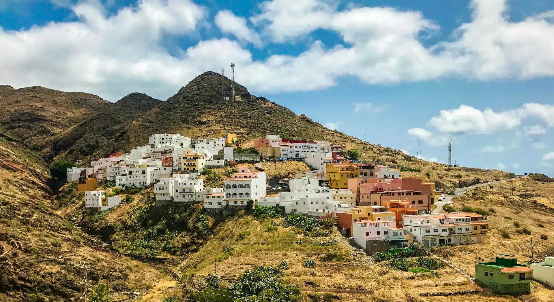 Caserío de casas blancas en la ladera de una montaña de Tenerife bajo un cielo con nubes